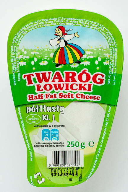 A package of Twaróg Łowicki half fat soft cheese, featuring a colorful design with a traditional Polish figure and a floral background.